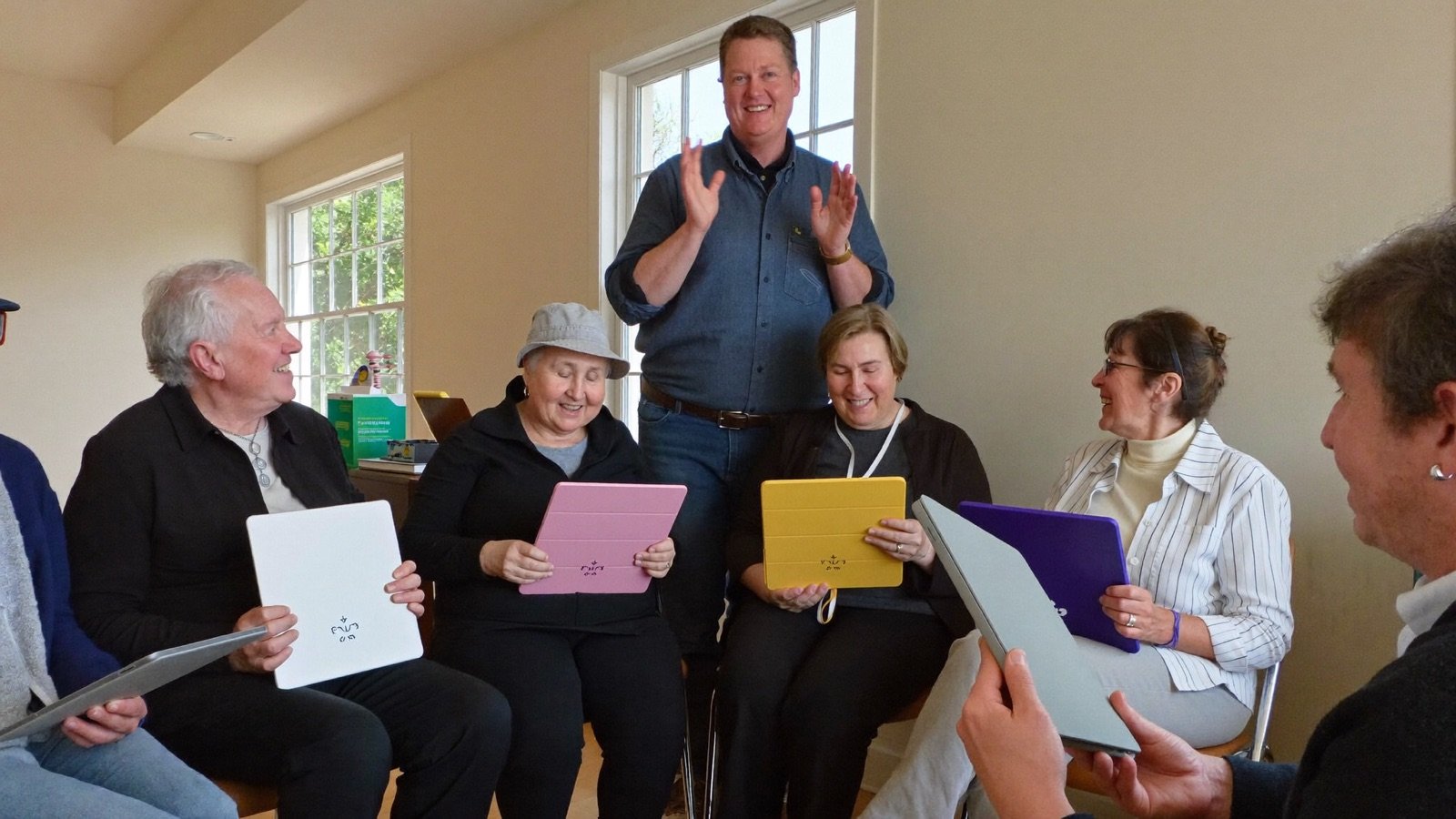 Older adults enjoy a friendly technology class in a bright community room.
